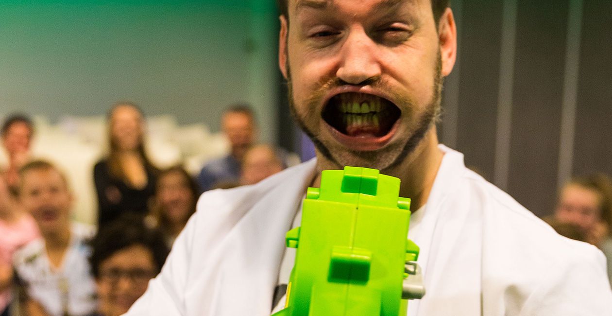 Mad scientist using a green air blower, blowing his mouth wide open