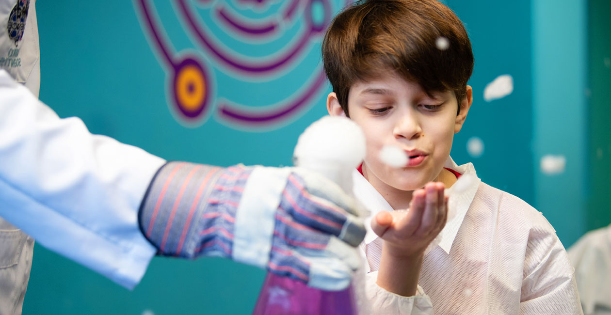 Boy blowing soap bubbles at a birthday party, after a dry ice experiment.